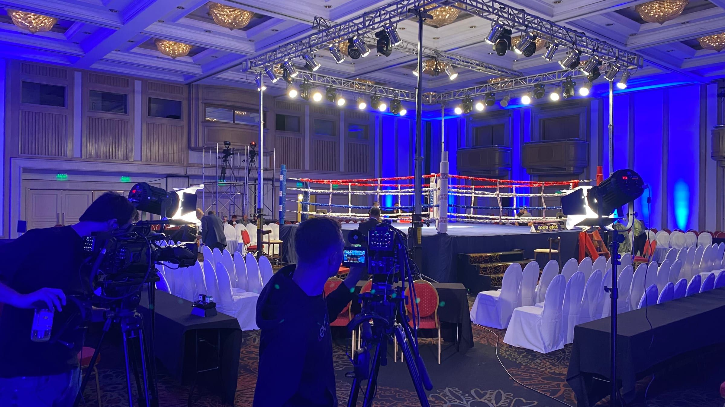 Dos camarógrafos de Estudio9 junto al ring, con las luces azules del salón del Radisson antes de la velada de boxeo